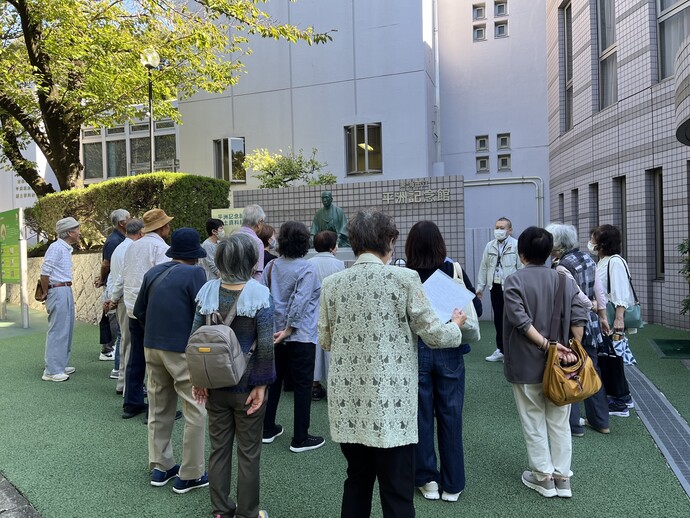 細井平洲像前で説明を聞く東郷町老人会の皆さんです。